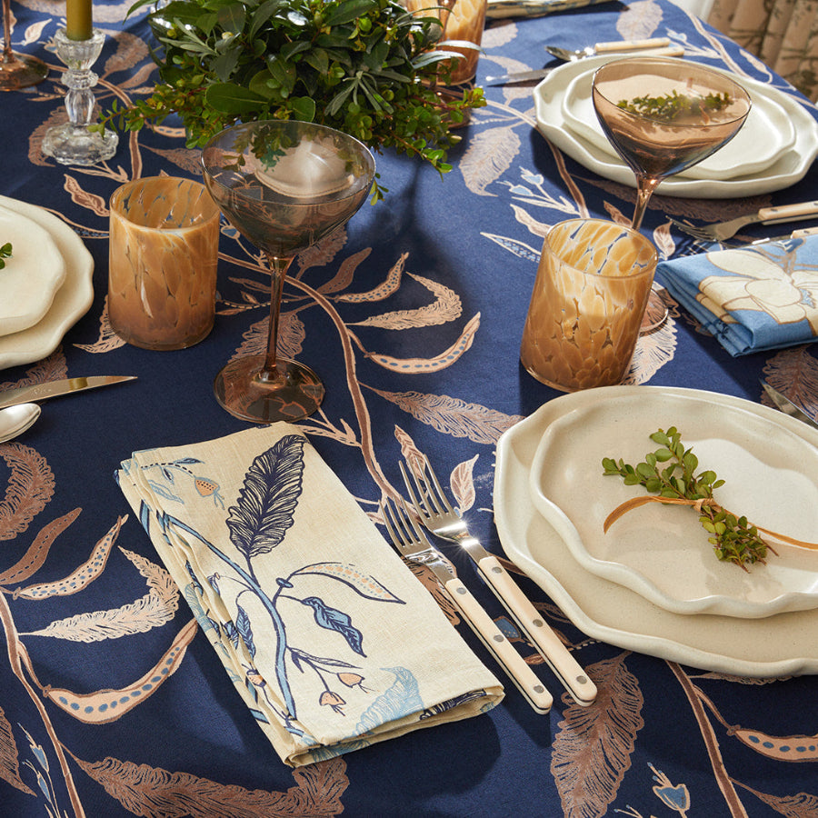 cream and blue tablecloth with floral design with plates, utensils, and garnish