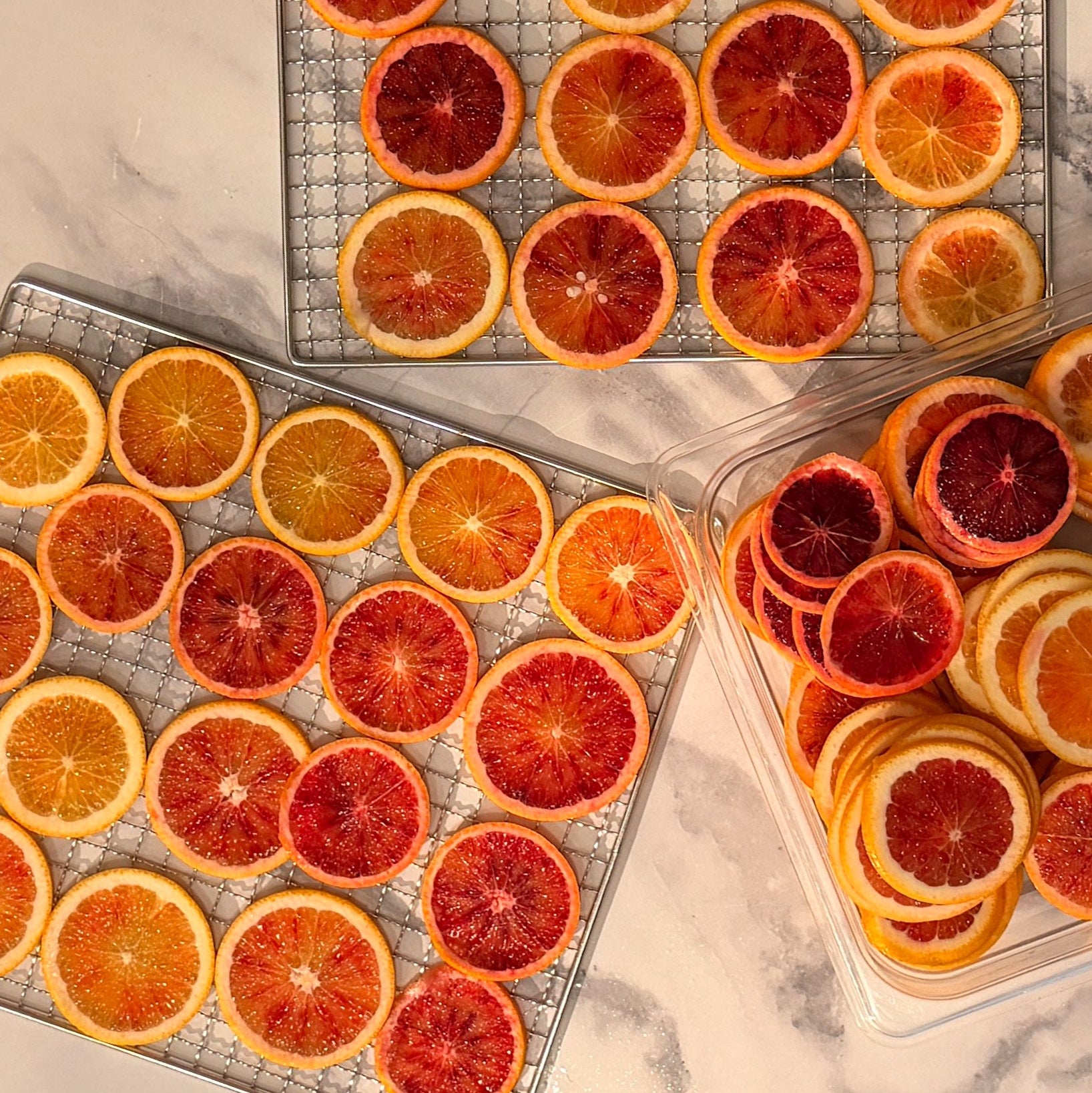 Sliced oranges on wire racks on a marble surface
