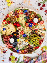 Load image into Gallery viewer, 16&quot; round cheese and charcuterie board overhead photo with fruit and herbs surround and checkered napkin
